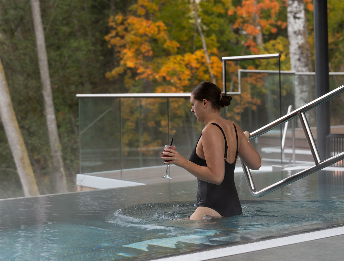 Tjej som njuter i de varma poolerna och blickar ut över Nissan i Riverside spa Hestraviken