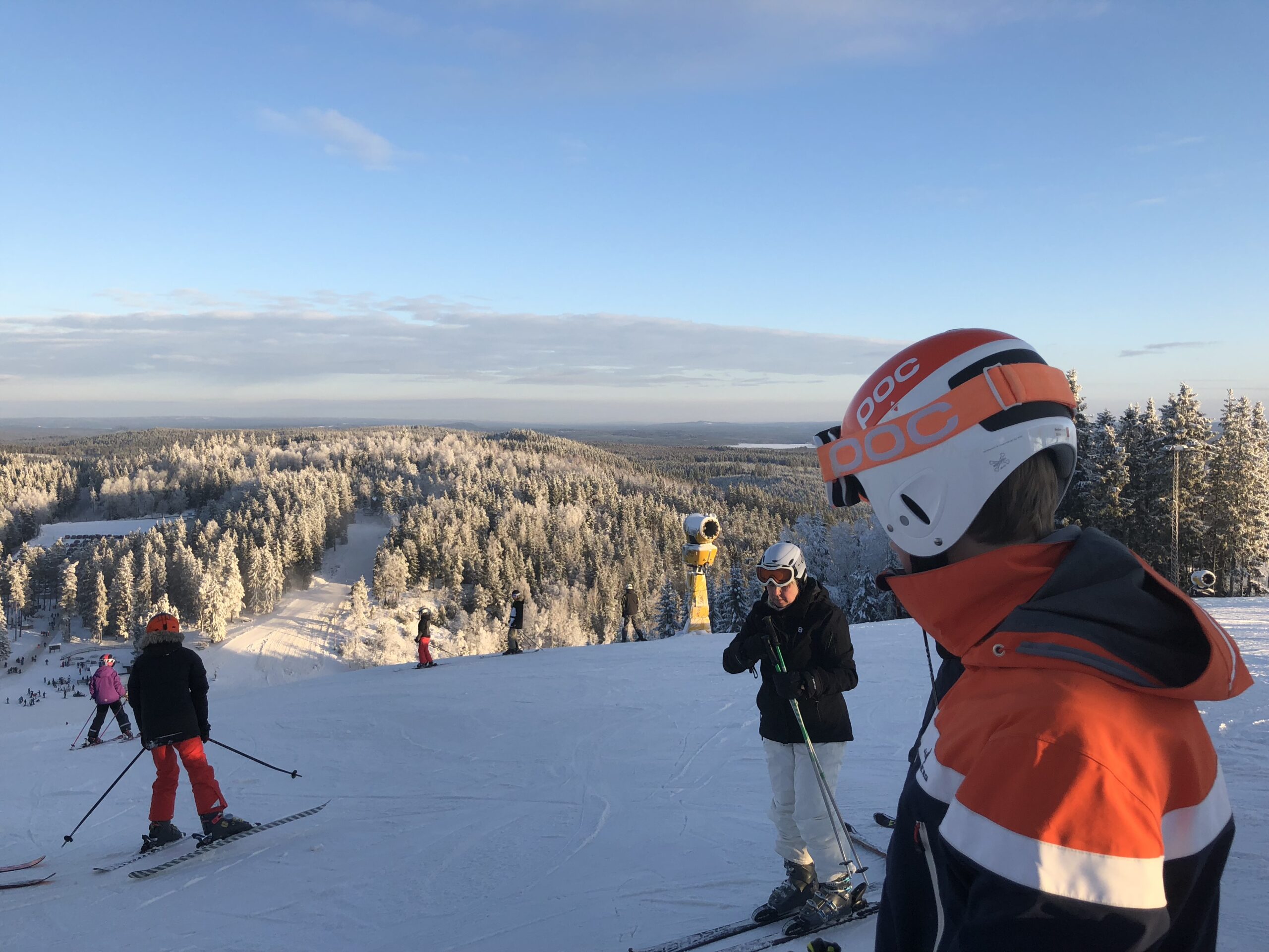 Skidåkare på toppen av Isaberg i Hestra ser ut över skidbackarna en solig vinterdag, med vidsträckt utsikt över Smålands landskap.