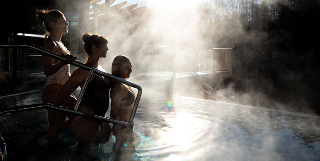 Tre damer i utomhuspoolen på Hestraviken hotell vid Isaberg, en vinterdag, som njuter av spa och den vackra naturen.