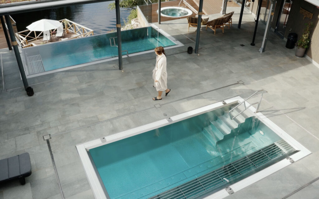 Två gäster promenerar på terrassen runt de varma utomhuspoolerna i Hestravikens Riverside Spa vid Isaberg i Småland.