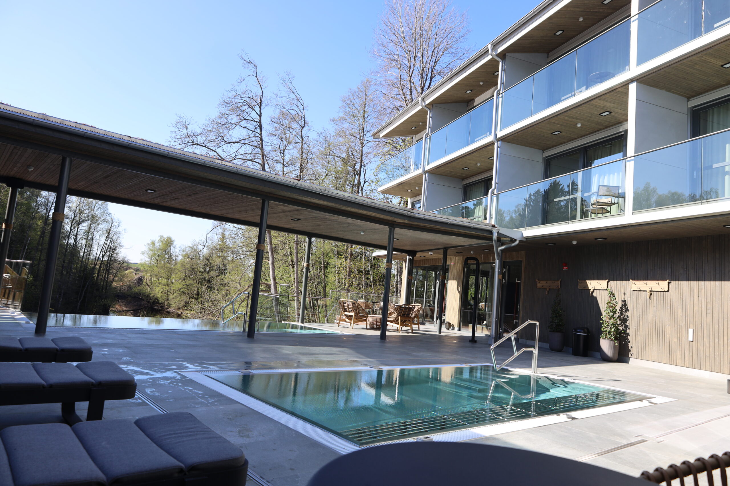 Vy över Riverside Spa Villan taggen från vårt spa café med infinitypool, solstolar samt våra Deluxerum med balkong ut över spa och ån Nissan