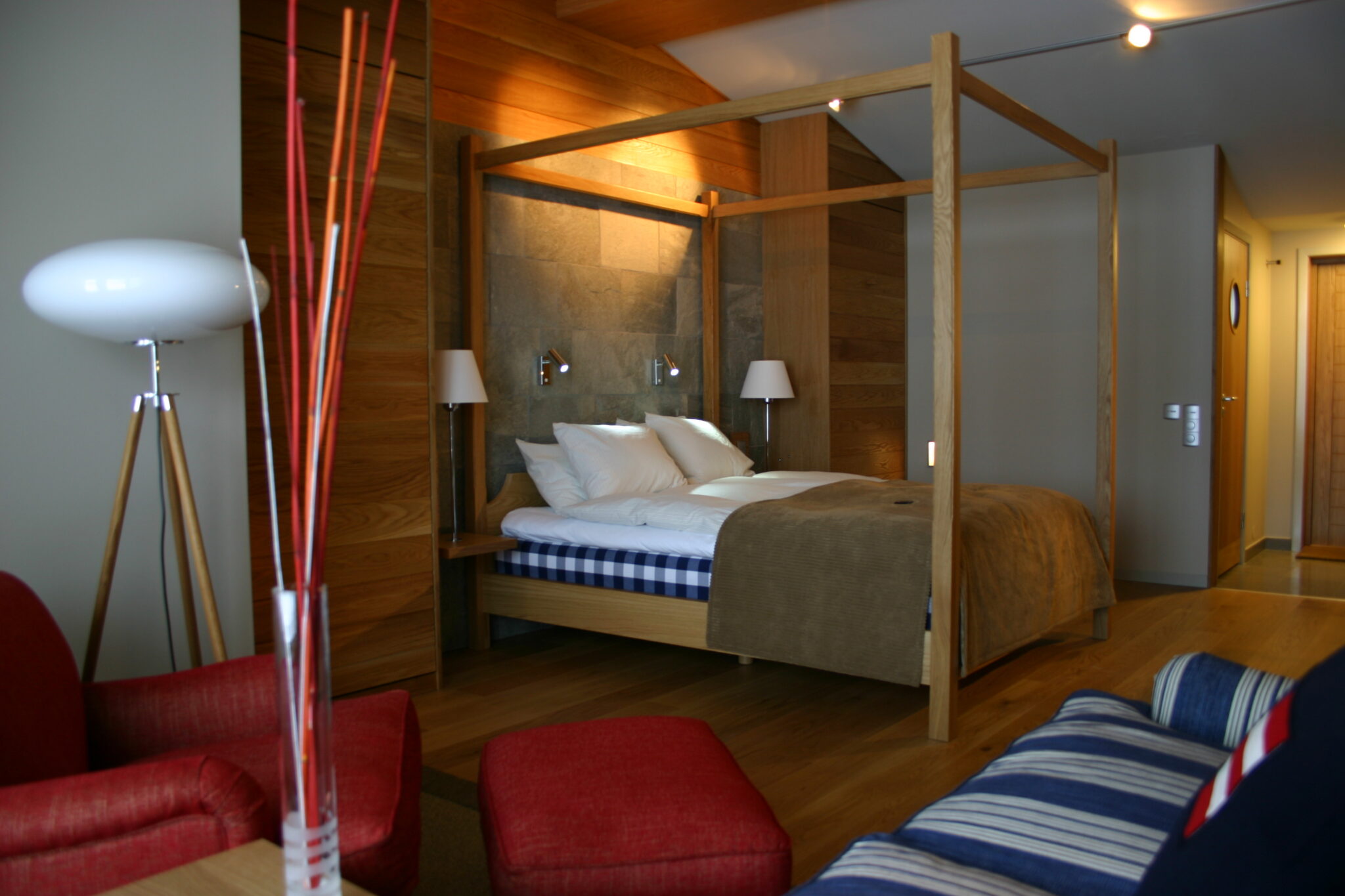 mjuka fluffiga kuddar och täcken, granitvägg med läslampor, soffgrupp och vilsam fåtölj samt golvlampa i elipsform