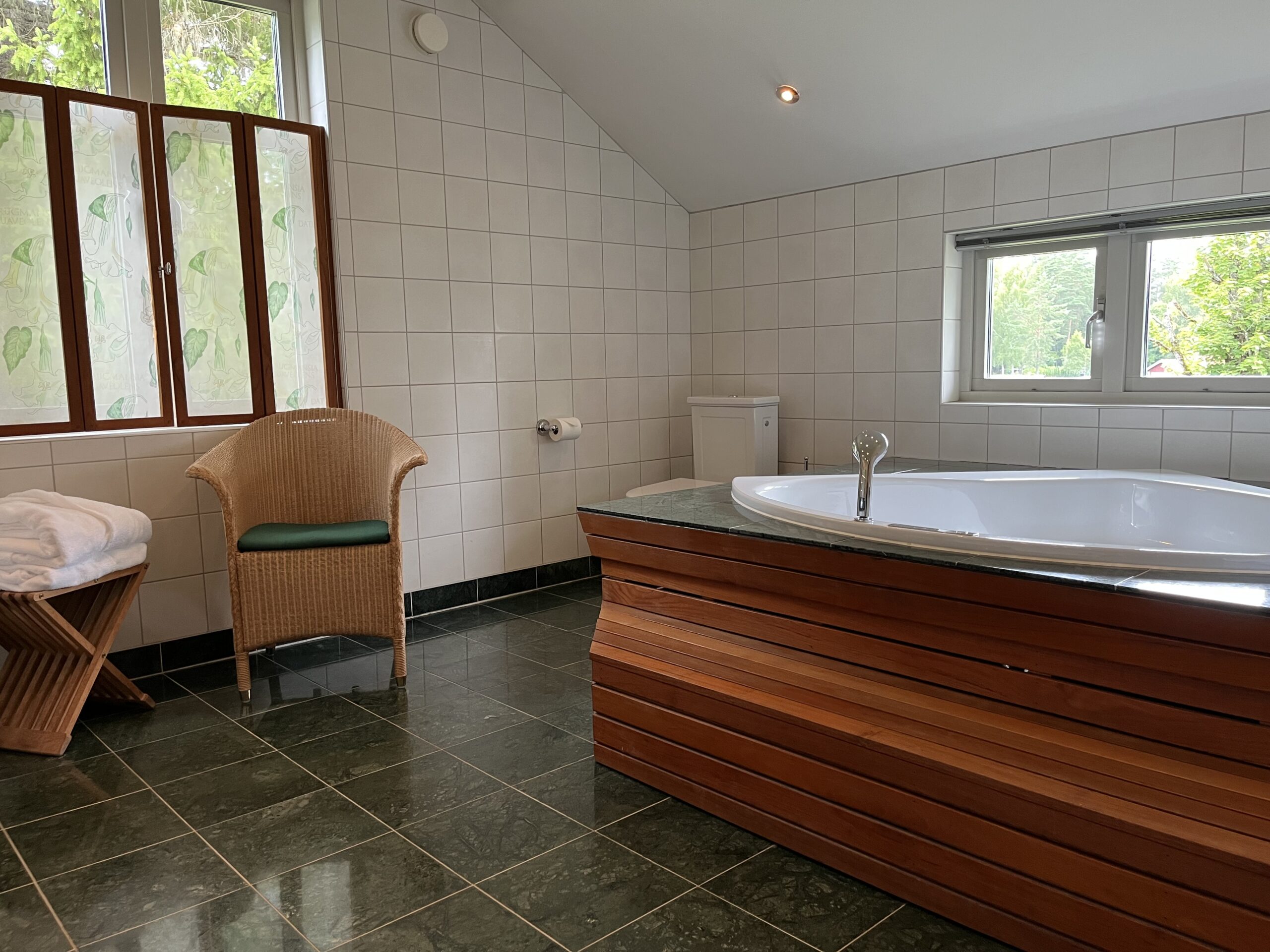 Hörnbadkar och trappa i teak i ett badrum i juniorsvit deluxe på Hestraviken Hotell & Spa vid Isaberg i Småland.