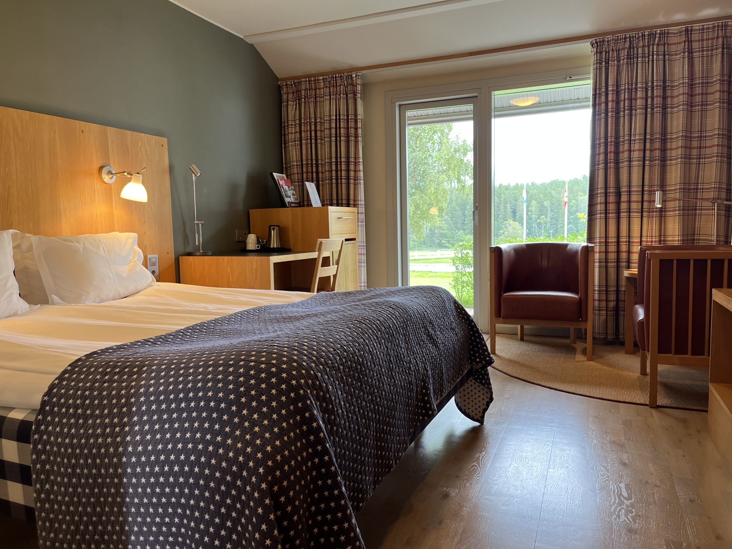 Interiör dubbelrum standard, Hästens dubbelsäng, clubfåtöljer i skinn, skrivbord med vattenkokare samt altandörr ut till terassen