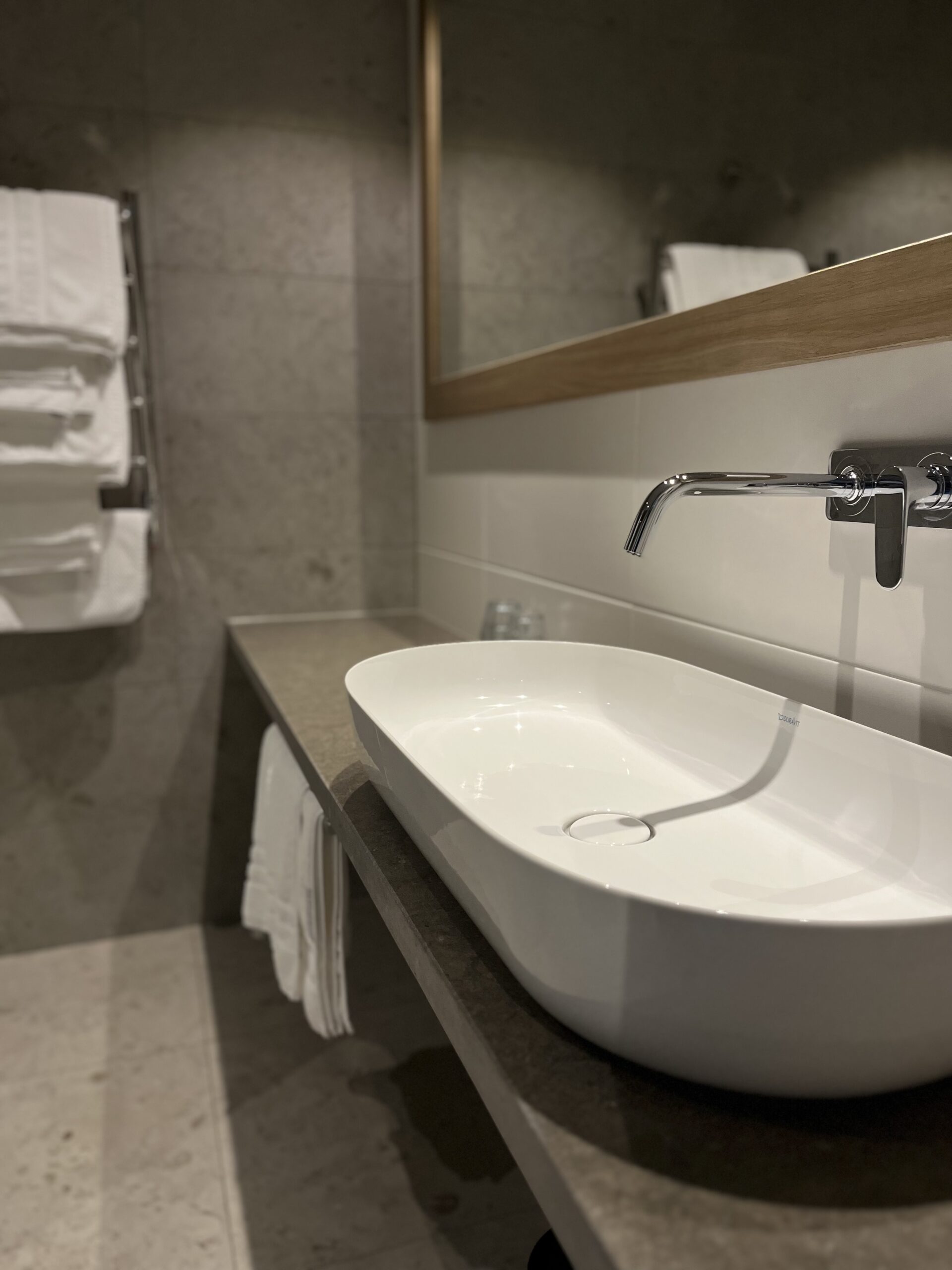 Generöst handfat i badrum i SpaVillan, stor spegel samt handukstork med fluffiga badhanddukar