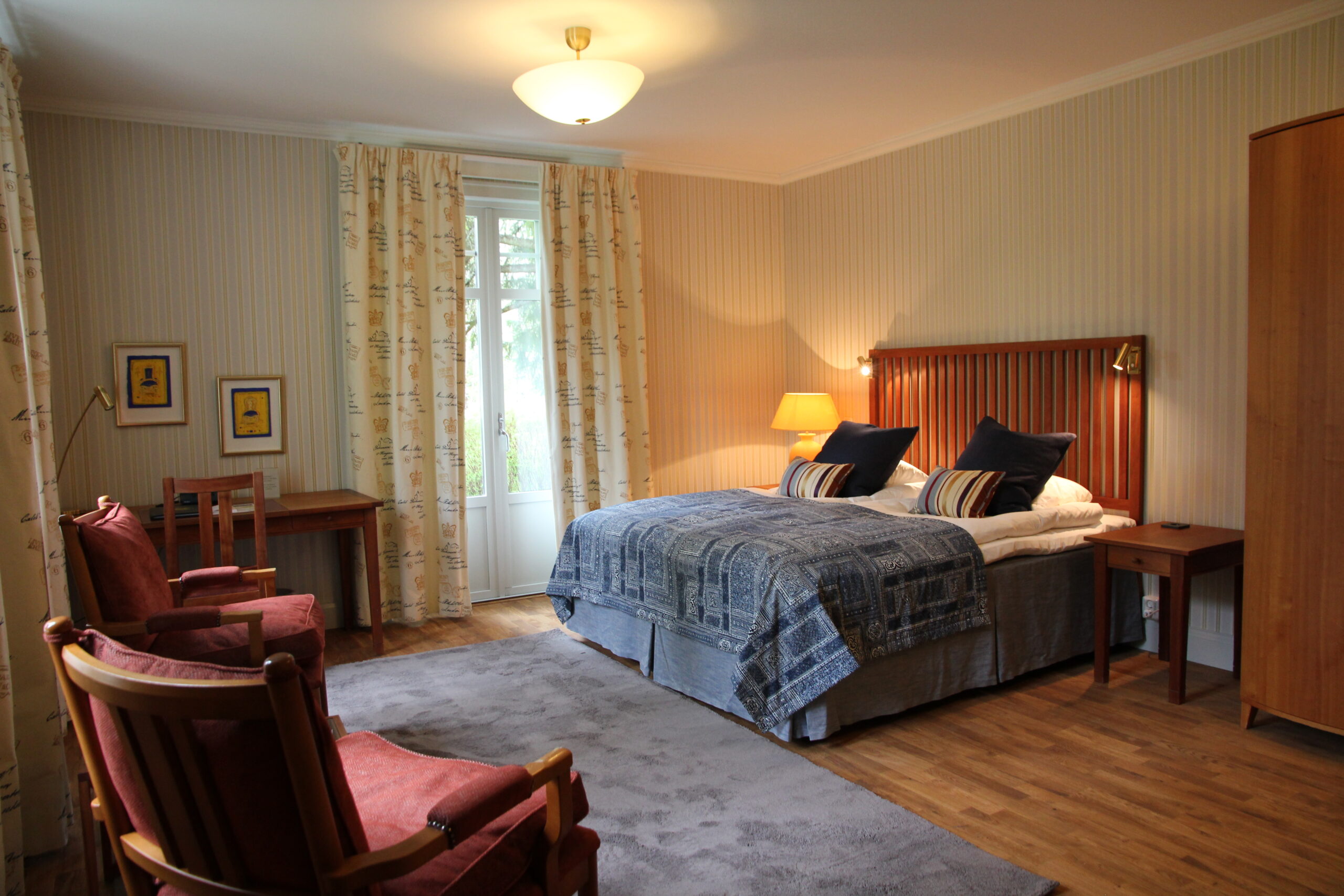 Interiör Dubbelrum Superior i Herrgårdsvillan, continentalsäng med fluffiga kuddar och täcken, sittfåtöljer, skrivbord samt fristående klädskåp