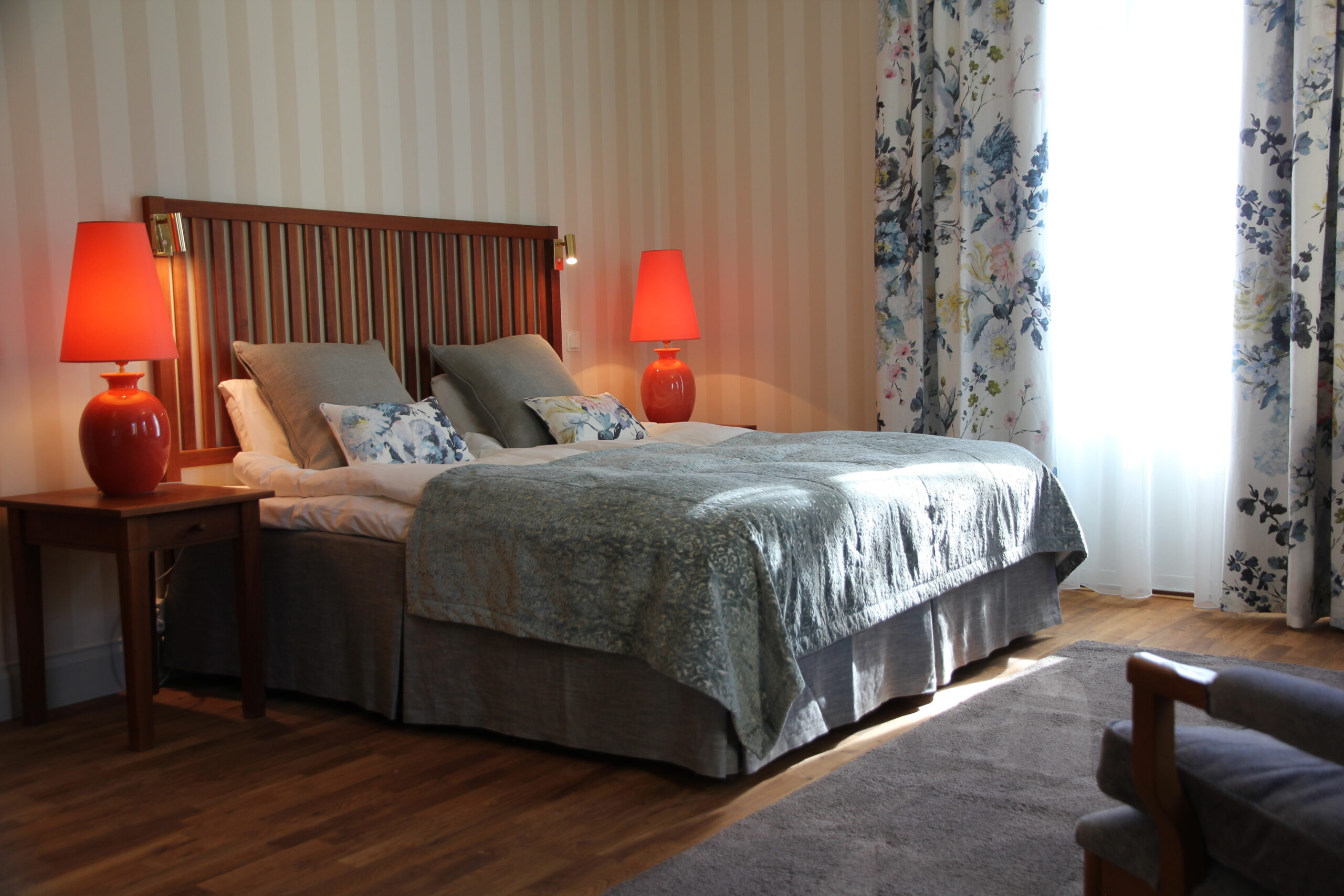 Vackert hotellrum i herrgårdsvillan. Dubbelsäng med sänggavel i teak. Blommiga gardiner. Lyxigt rum på Hestraviken Hotell och Spa vid Isaberg i Småland.