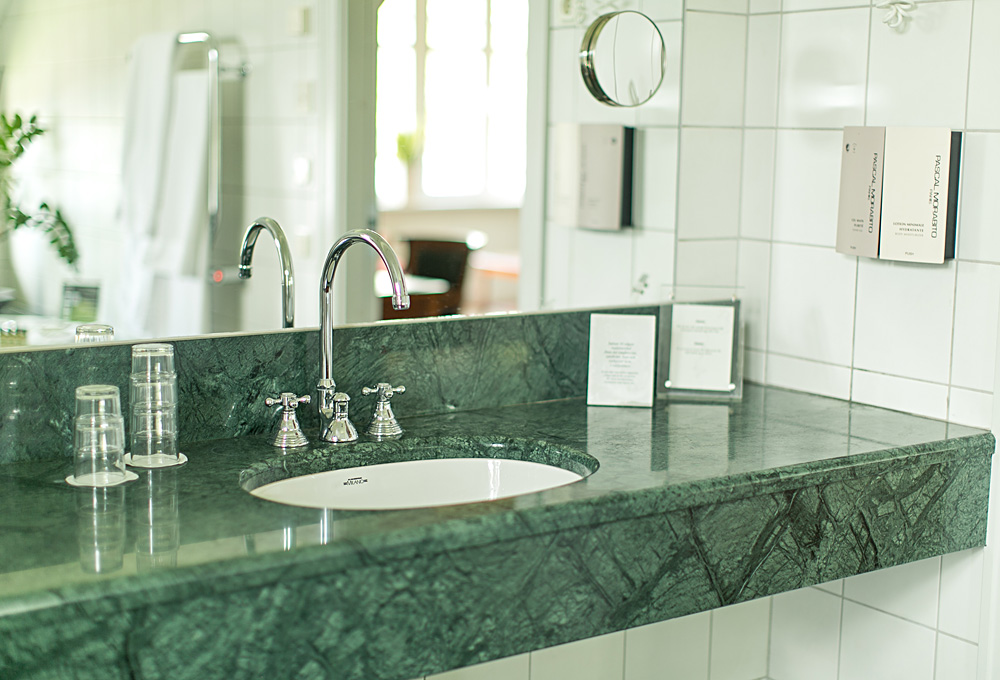 På bilden syns ett handfat och kran omgivna av italiensk marmor. Badrum i svit penthouse i herrgårdsvillan på Hestraviken hotell och spa vid Isaberg I Småland.