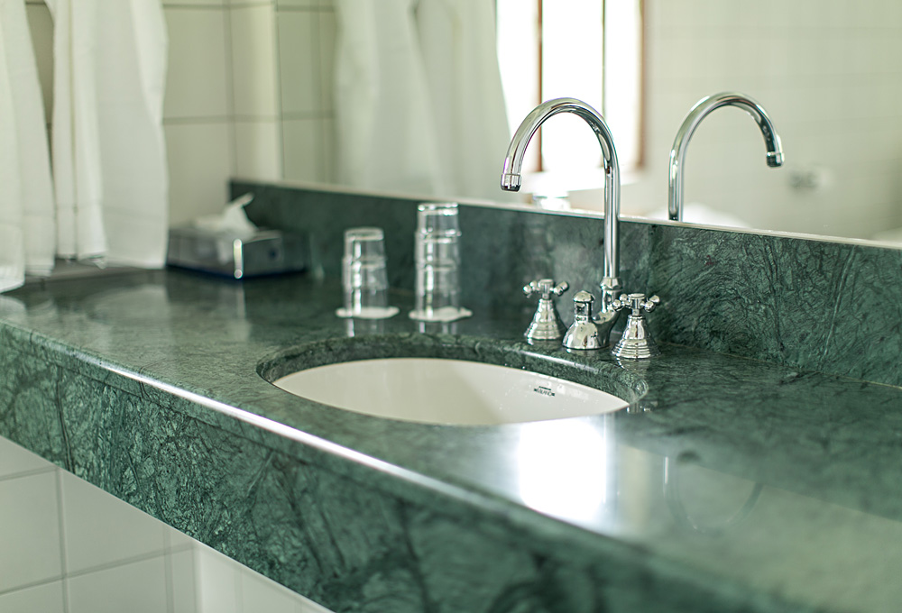 Kran och handfat, grön marmor och spegel på Hestraviken Hotell och Spa nära Isaberg i Småland