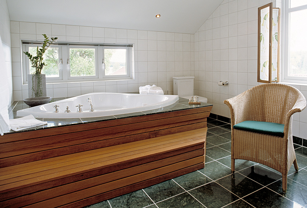 Hörnbadkar och trappa i teak i ett badrum i svit penthouse på Hestraviken Hotell & Spa vid Isaberg i Småland.