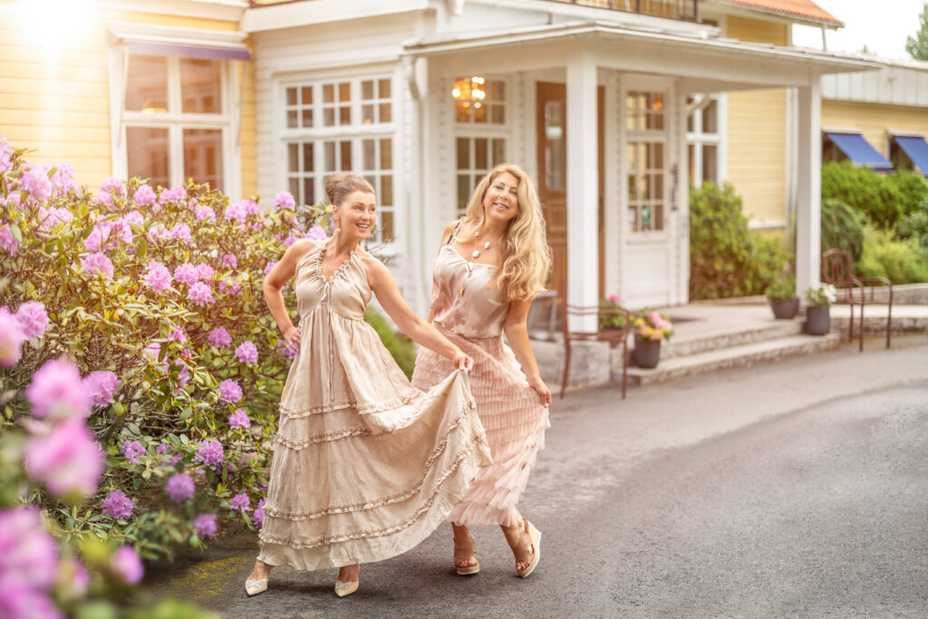 Bröllop och fester på Hestraviken hotell i Småland. Två eleganta damer i klänning framför entrén till restaurangen