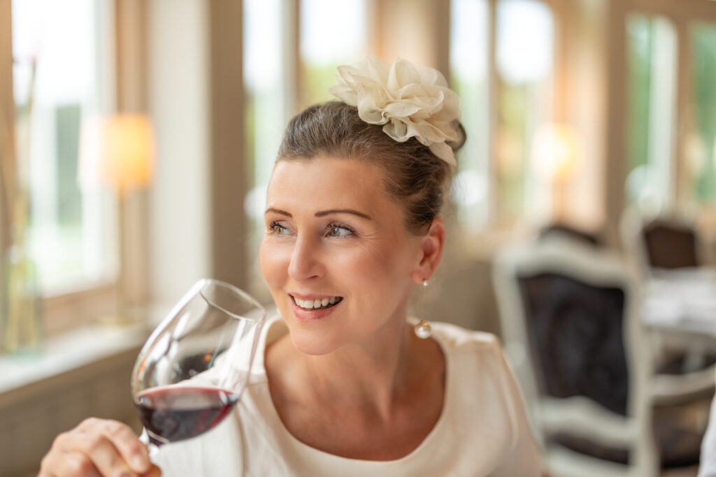 Kvinna som siter vid ett bord i matsalen och dricker vin