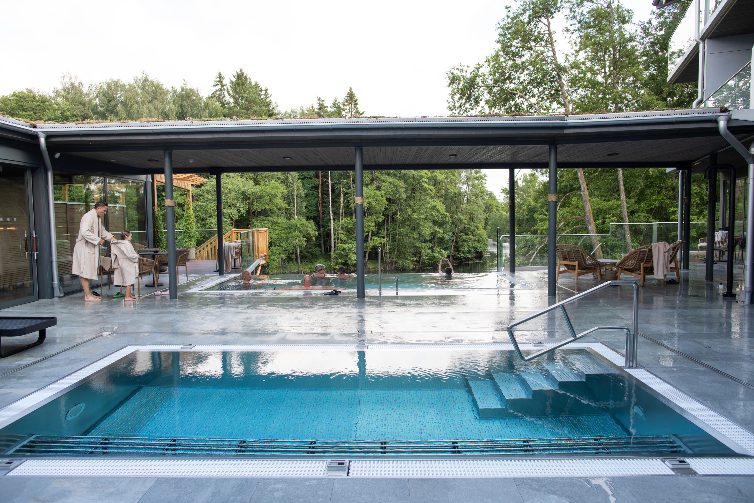 Pooler och terrass i Riverside spa med vuxna och barn som är redo för bad