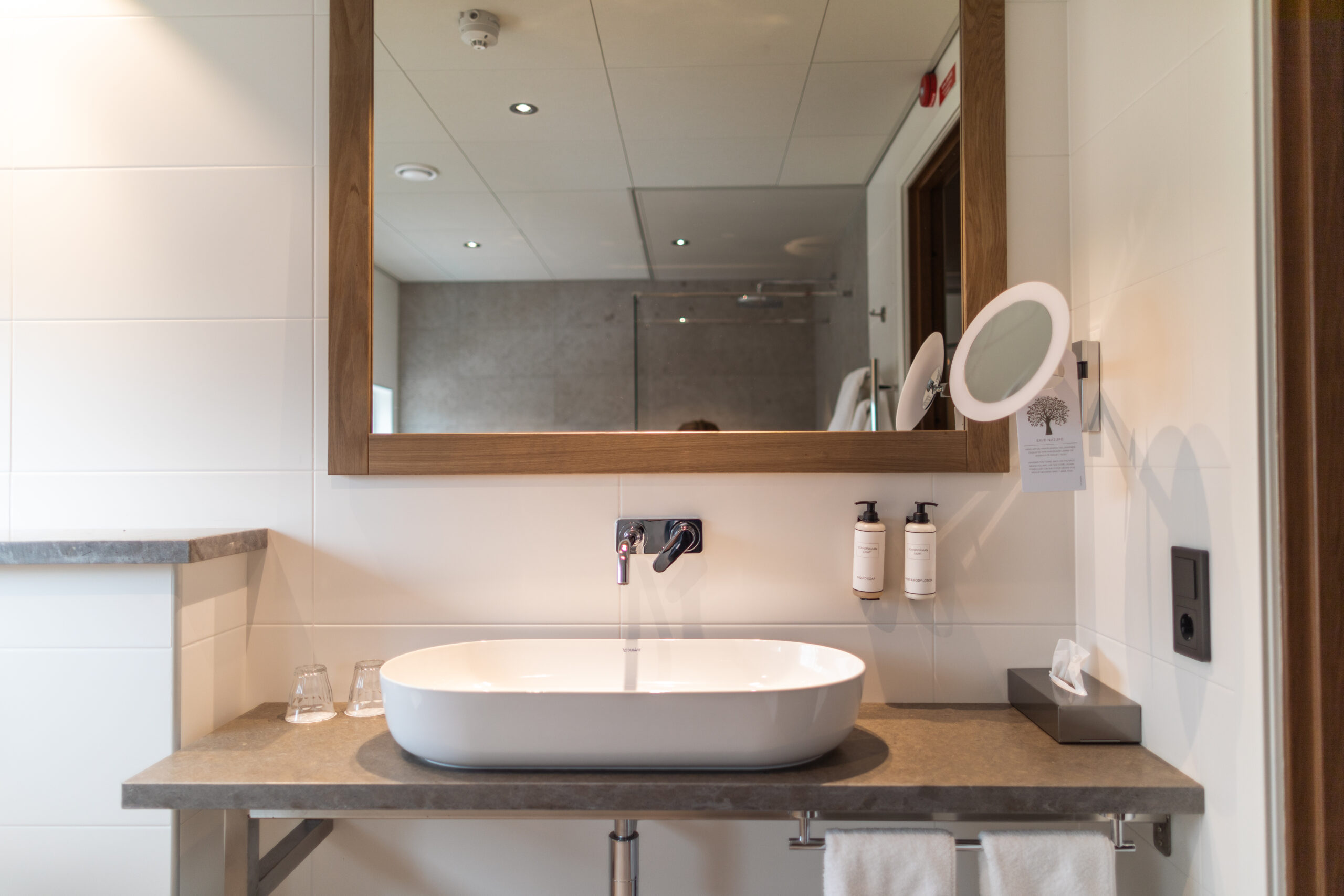 Interiör badrum i Riverside Spa villan, handfat med utvalda rengöringsprodukter samt sminkspegel