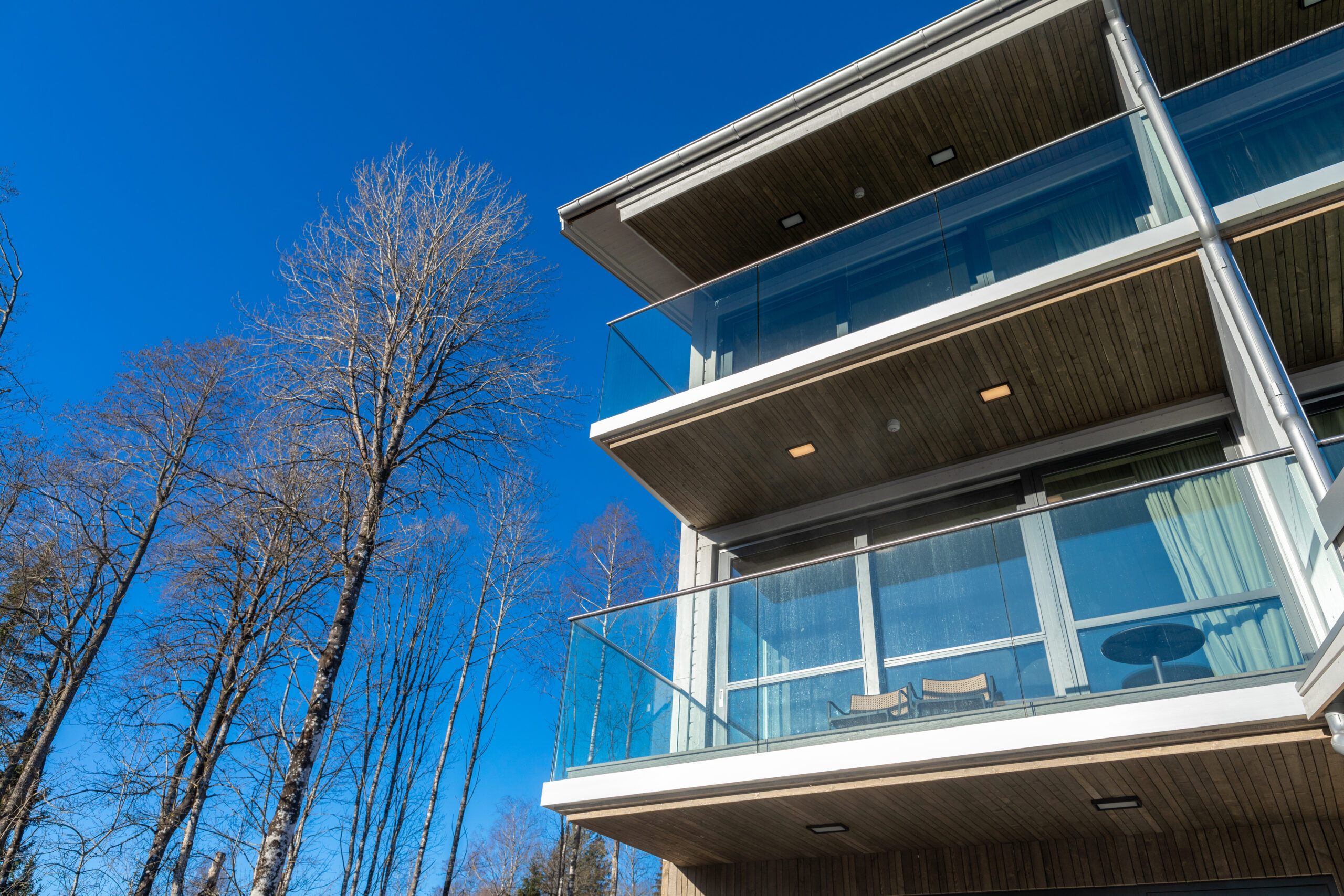 Deluxe Corner rum i Riverside spavillan en solig dag med klarblå himmel och björkar precis intill