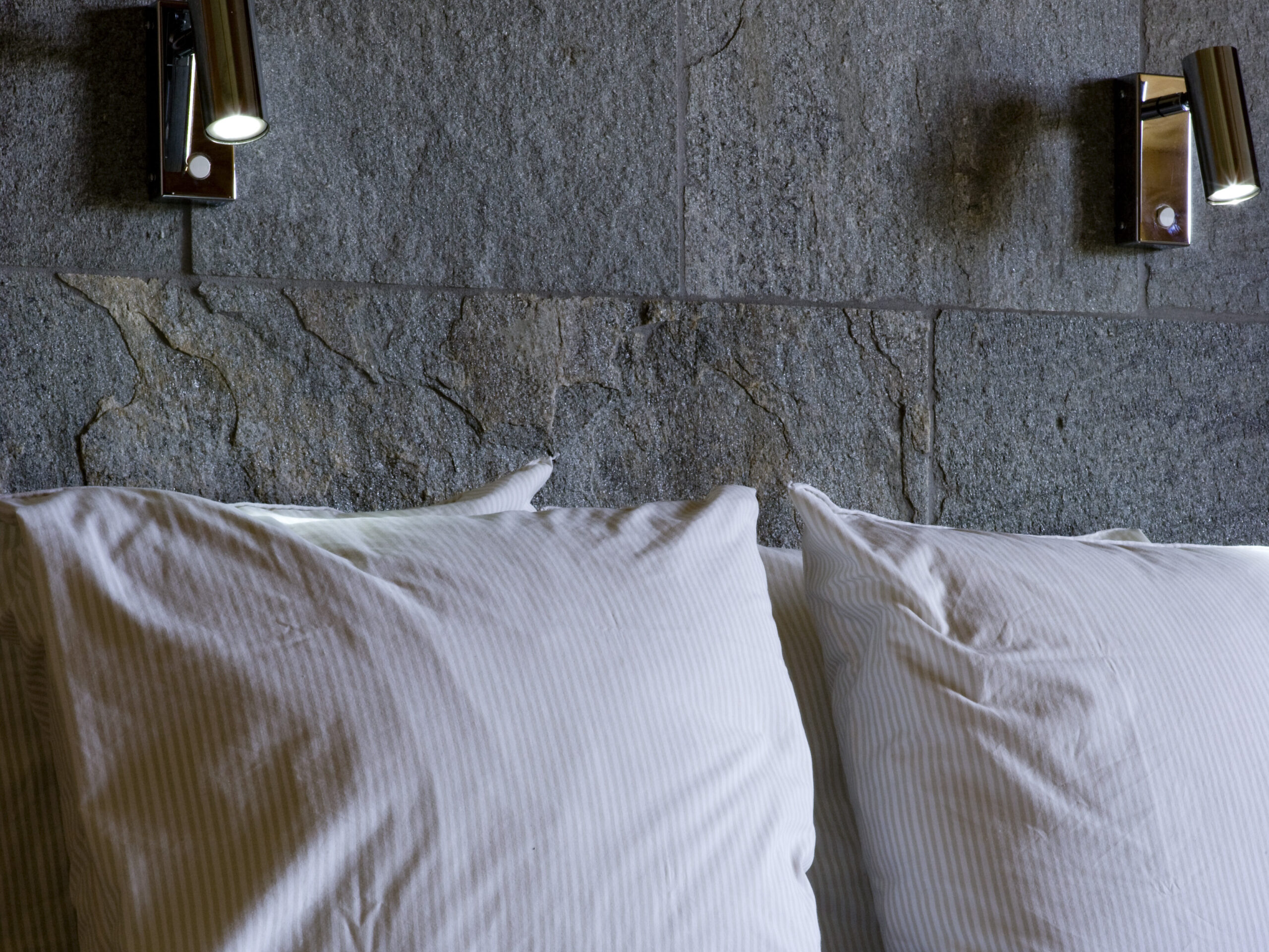 Granitvägg med läslampa och fluffiga kuddar i Dubbelrum Deluxe Villa 4