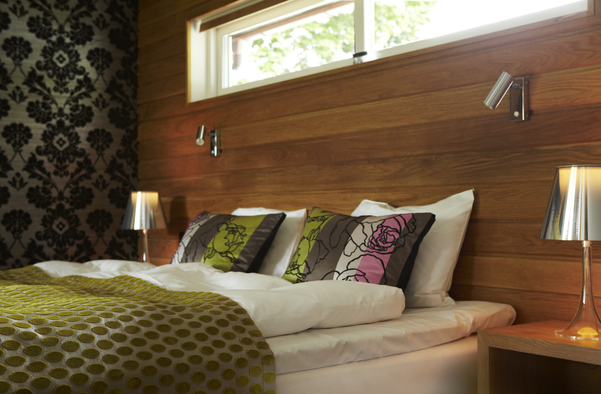 Hotellrum i Villa 2 på Hestraviken hotell i Småland. med säng och sänglampor.