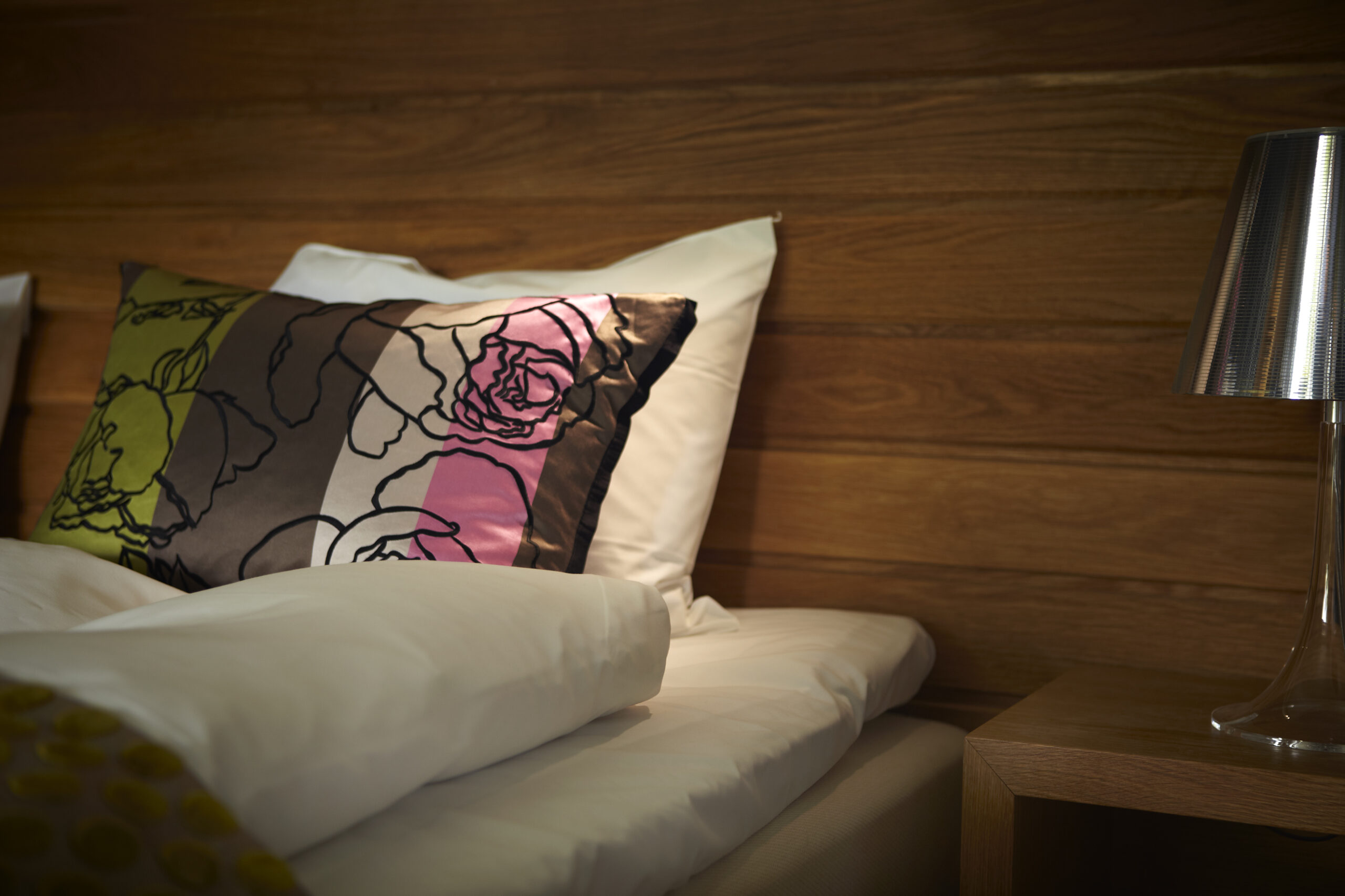 Närbild på kudde i vackra rosa, gröna och bruna färger i dubbelsäng på Hestraviken Hotell & Spa vid Isaberg i Småland,