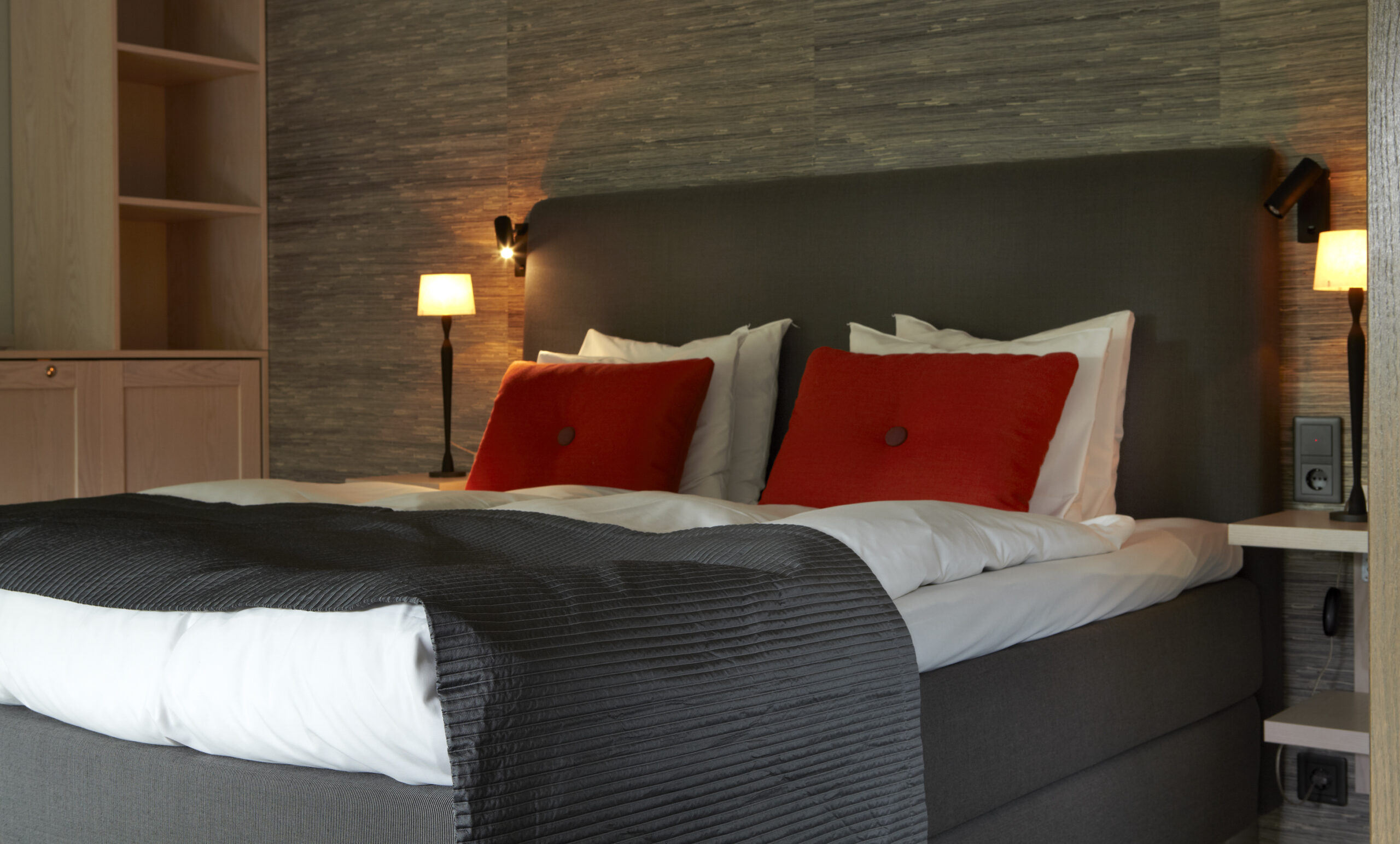 Carpe Diem Continental-dubbelsäng med orange prydnadskuddar från Hay. Lyxigt hotellrum på Hestraviken hotell och Spa vid Isaberg i Småland,