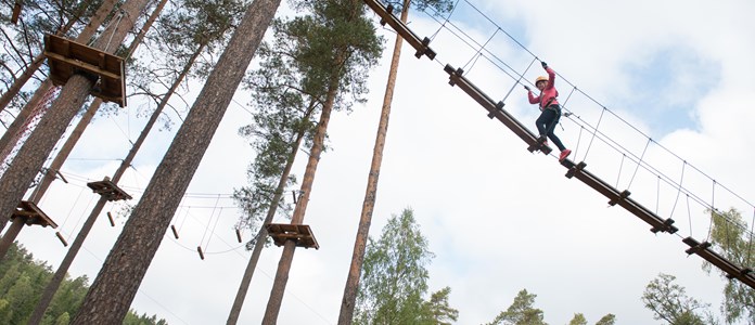 Kvinna klättrar en av höghöjdsbanorna på Isaberg. Flertal banor med olika svårighetsgrad för alla åldrar