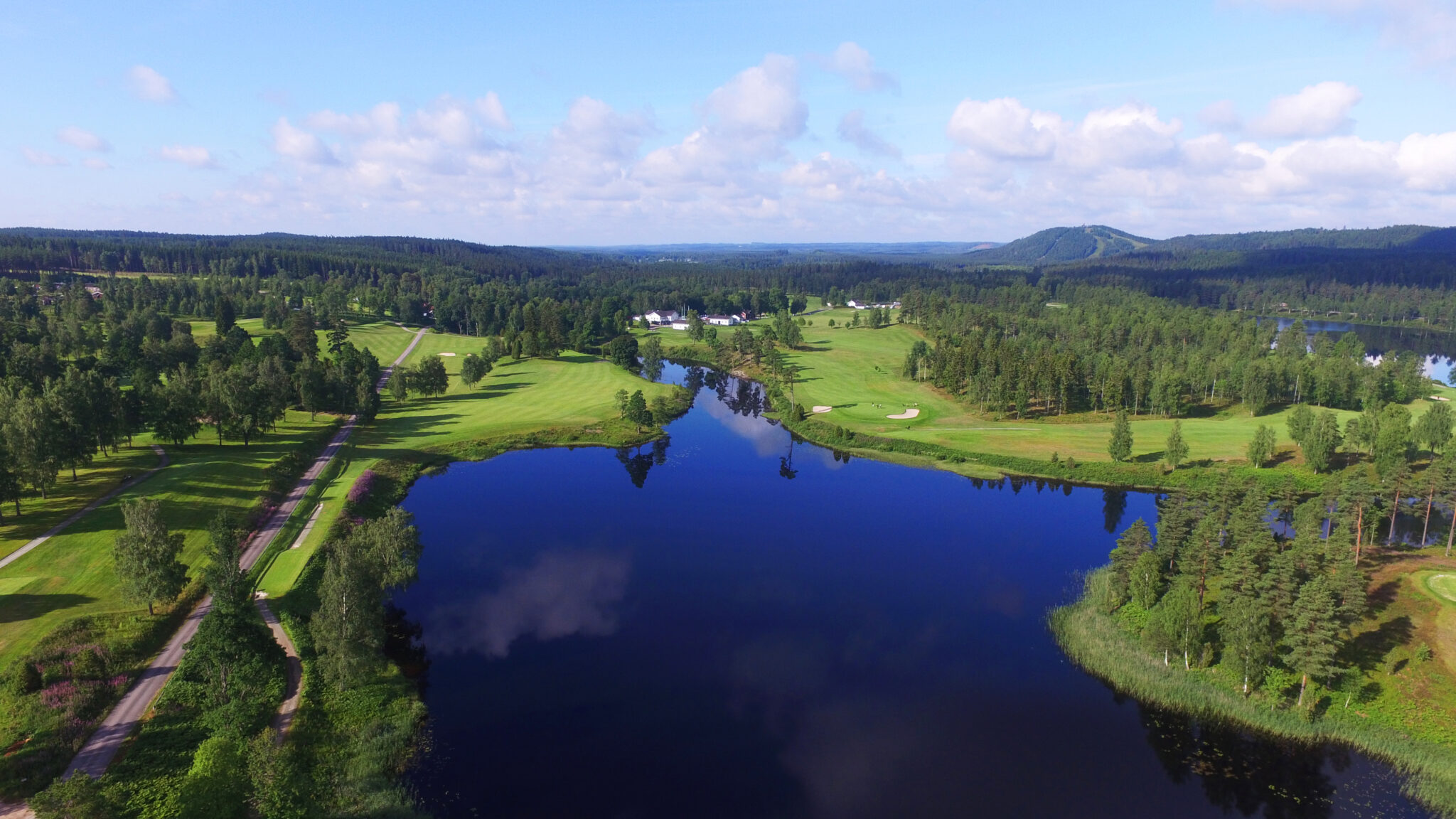 Magisk vy av Isaberg Golfklubb med Hammarsjön i förgrunden och Isaberg i fjärran, naturskön omgivning i hjärtat av Småland