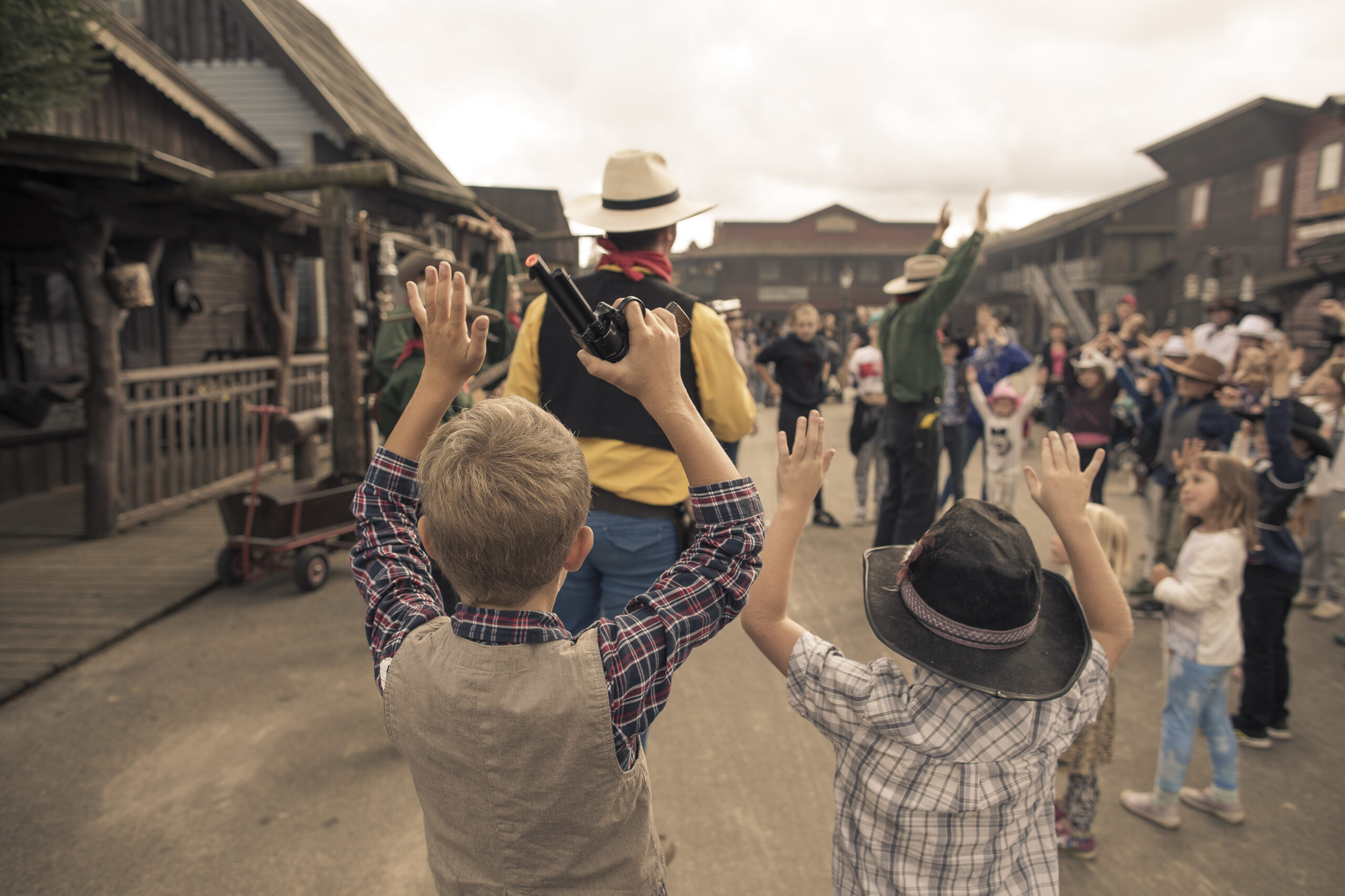 Barn som håller upp händerna och medverkar i Lucky Luke och bröderna Daltons show på huvudgatan i Västern staden High Chaparall
