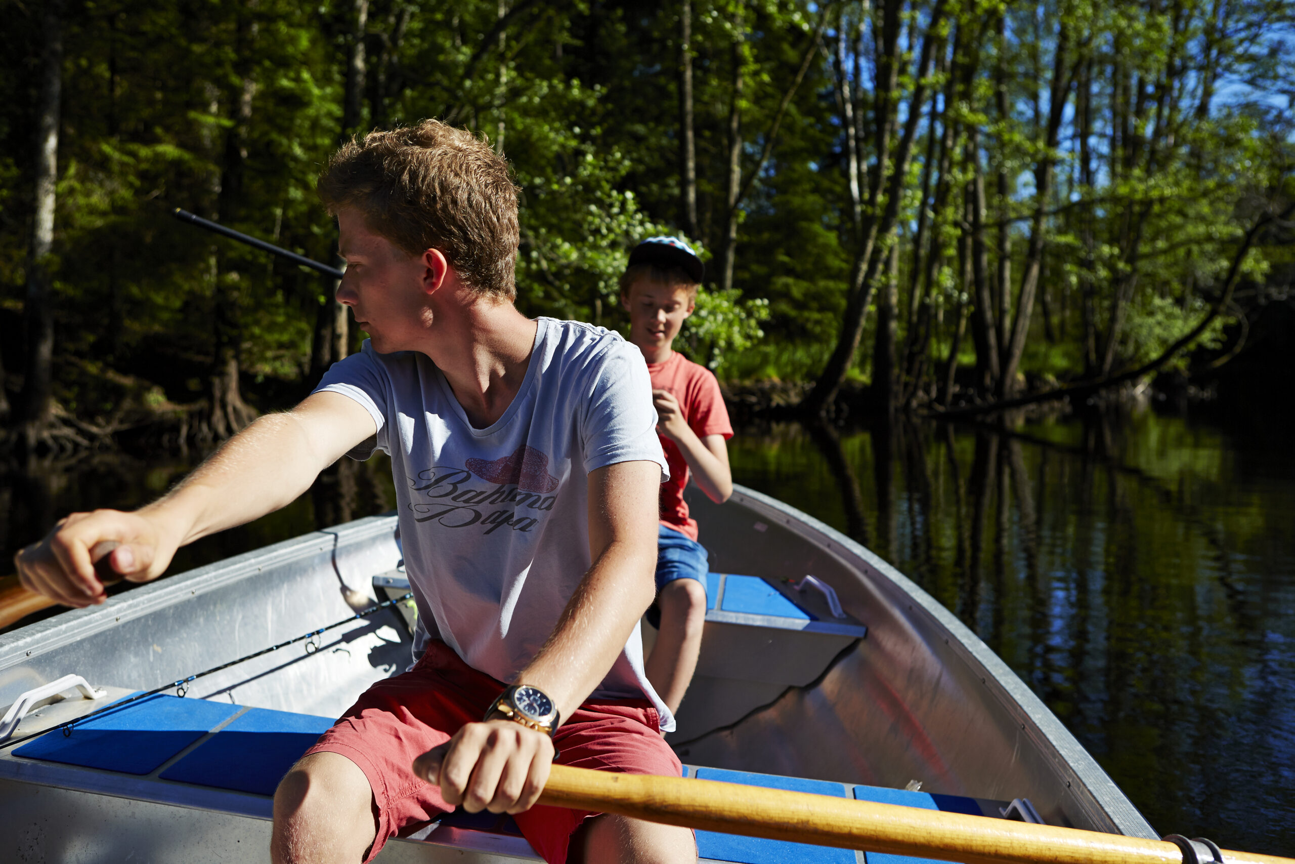 Två killar i roddbåt provar fiskelyckan en solig sommardag på Alugstorpasjön i närheten av Hestraviken