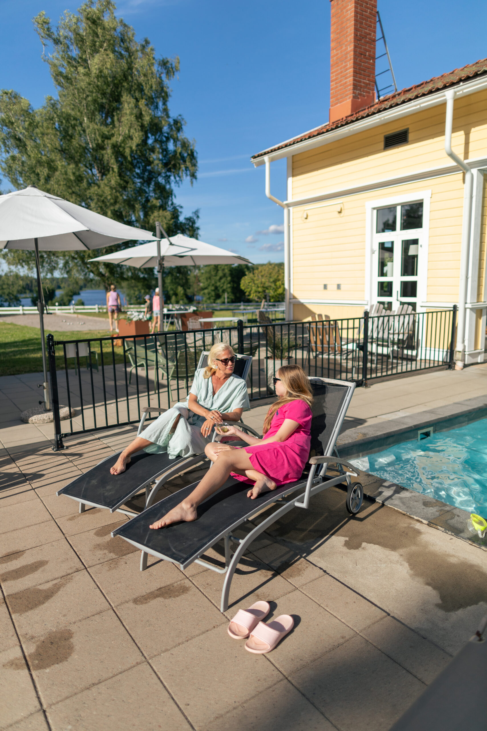 Kvinna och barn en sommar eftermiddag mitt vid utomhuspoolen bredvid restaurangen