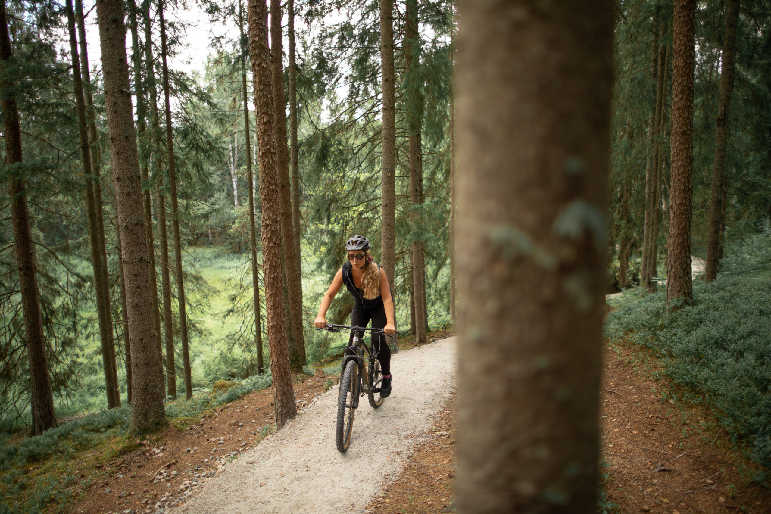 Kvinna på mtb cyklandes i skogen uppför en backe på preparerad bana vid Isaberg