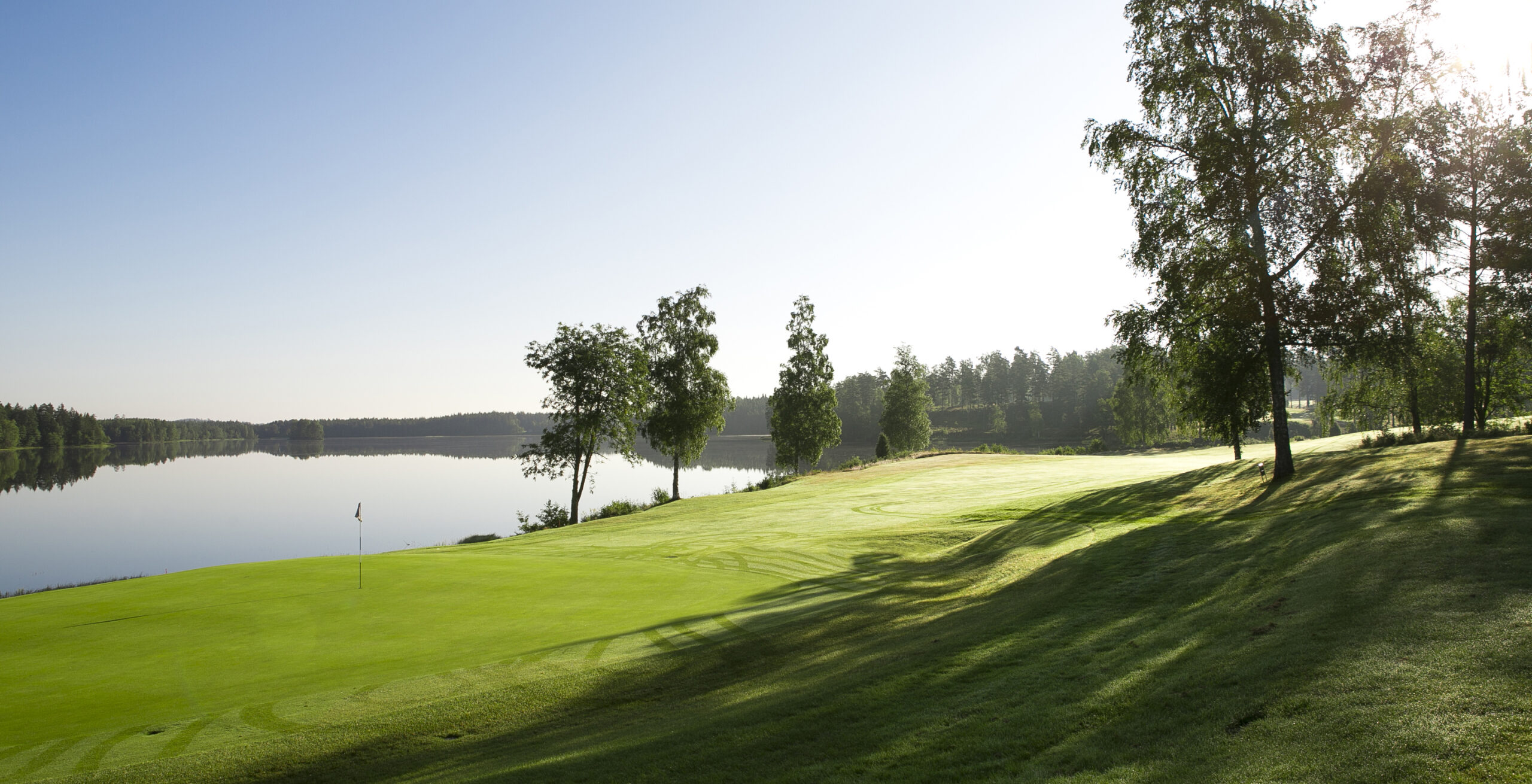Soluppgång över Isaberg GK och Hammarsjön med grönskande fairways och greener i naturskönt område i hjärtat av Småland