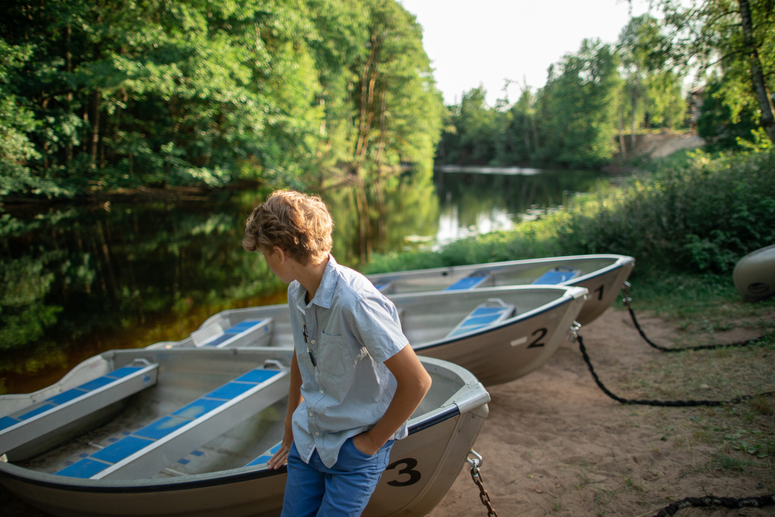 Kille vid roddbåtar på Hestraviken hotell vid Isaberg, blickar ut över Nissan och omgivningarna – en perfekt plats för äventyr och avkoppling.