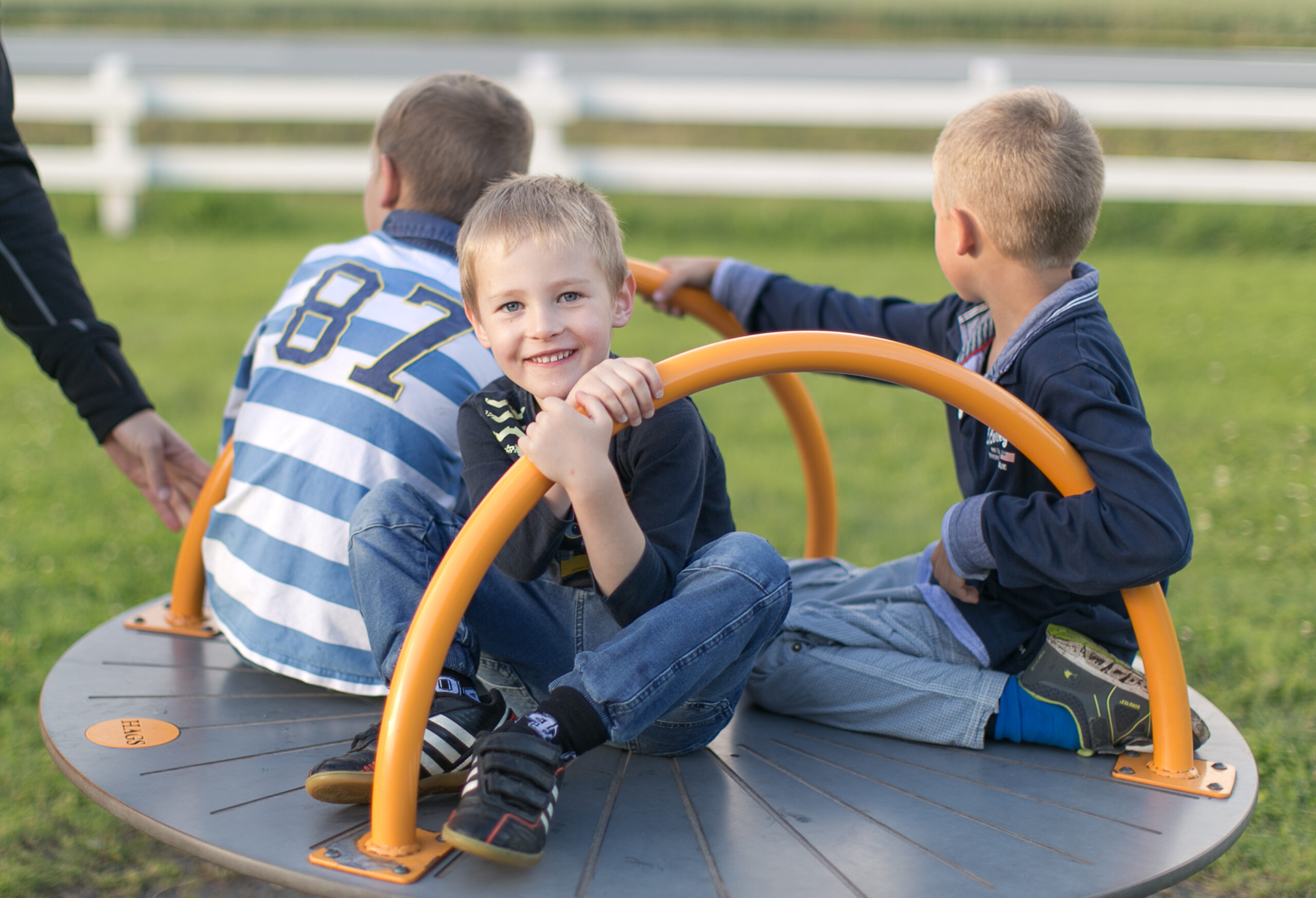 Tre barn leker i karusellen på lekplatsen i trädgården på Hestraviken hotell.