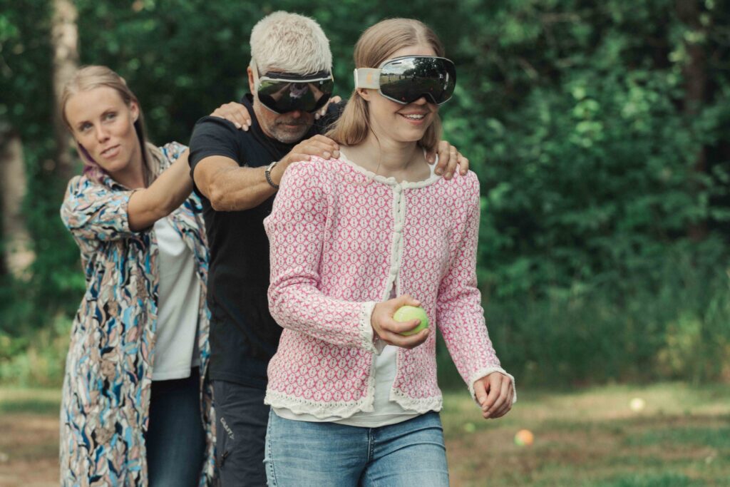 Deltagare i rad med förbundna ögon ledsagas av en kollega, det utlovas goda och många skratt i denna teambyggande aktivitet på Hestraviken