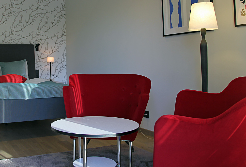 Dubbelsäng samt sittgrupp med fåtöljer och golvlampa i Dubbelrum Riverside Villa 5