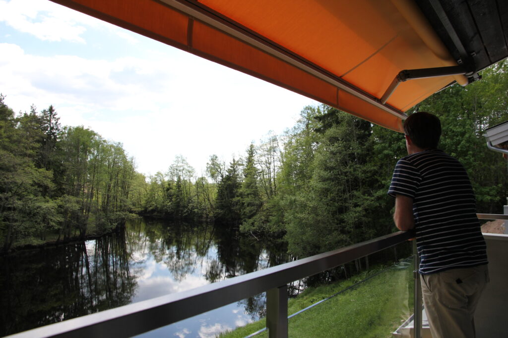 Man på balkong i Deluxe Riverside rum i Villa 5 med utsikt över ån Nissan