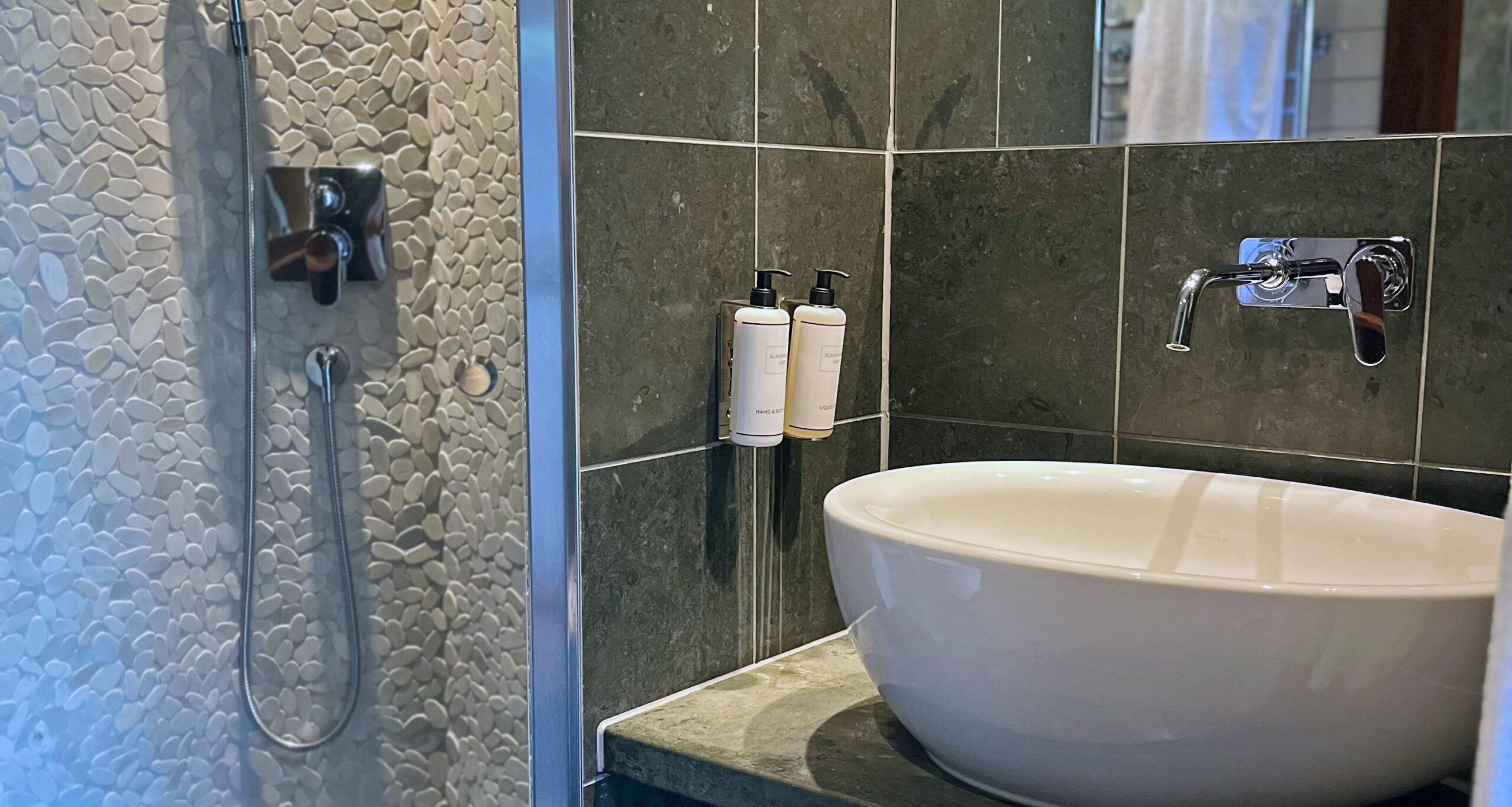 Handfat och dusch i badrum i ett av hotellrummen i villa 2 på Hestraviken hotell och spa vid Isaberg i Småland