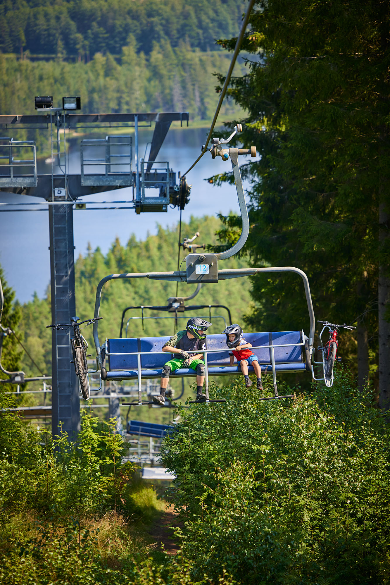 Pappa och son i sittlift med mtb cyklar på väg uppför Isaberg