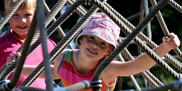 Barn leker i ett klätternät på en lekplats i närheten av Hestraviken