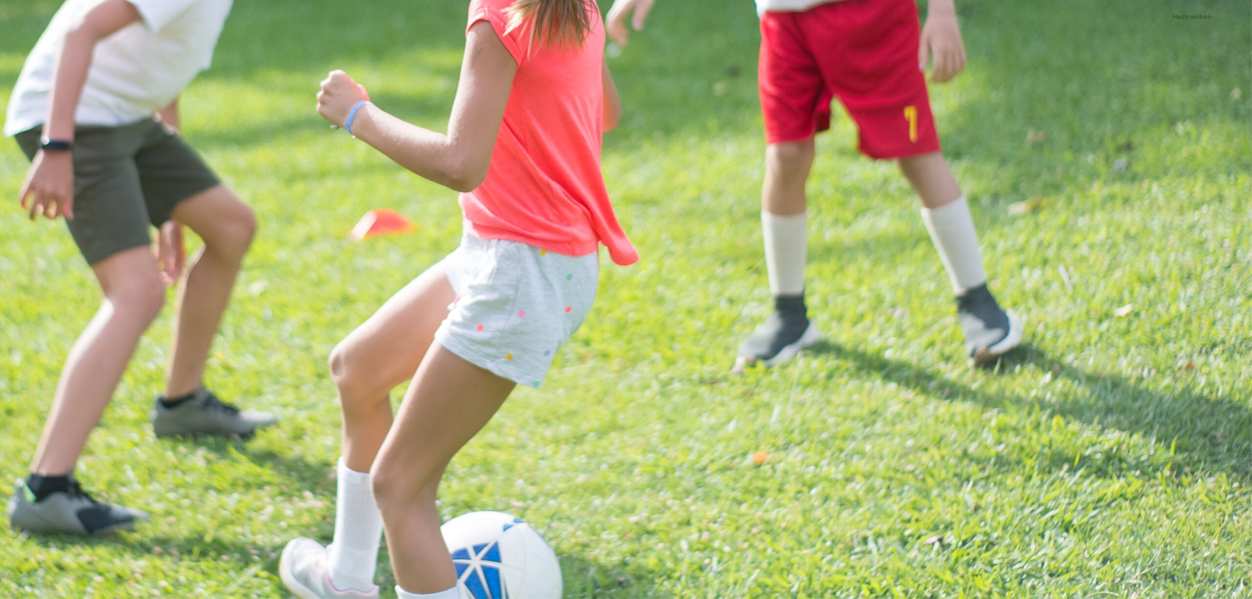 Tre barn spelar fotboll i vår trädgård på Hestraviken hotell, en rolig och säker plats för barn att utforska under er familjesemester i Småland.