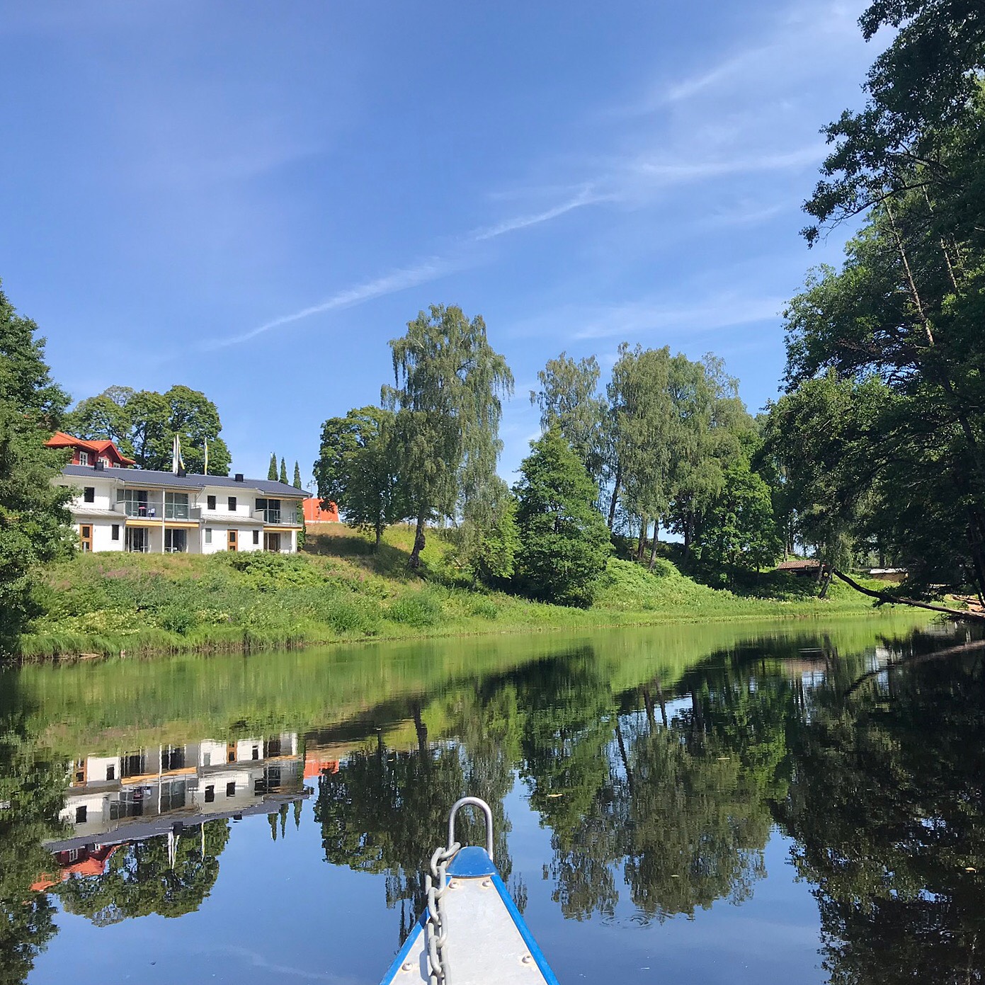 Vy från kanotister som tar sig fram på Nissan en klar sommardag, Riverside rum i Villa 5 med balkong och terass ligger inbäddad i grönska och skymtar i bakgrunden