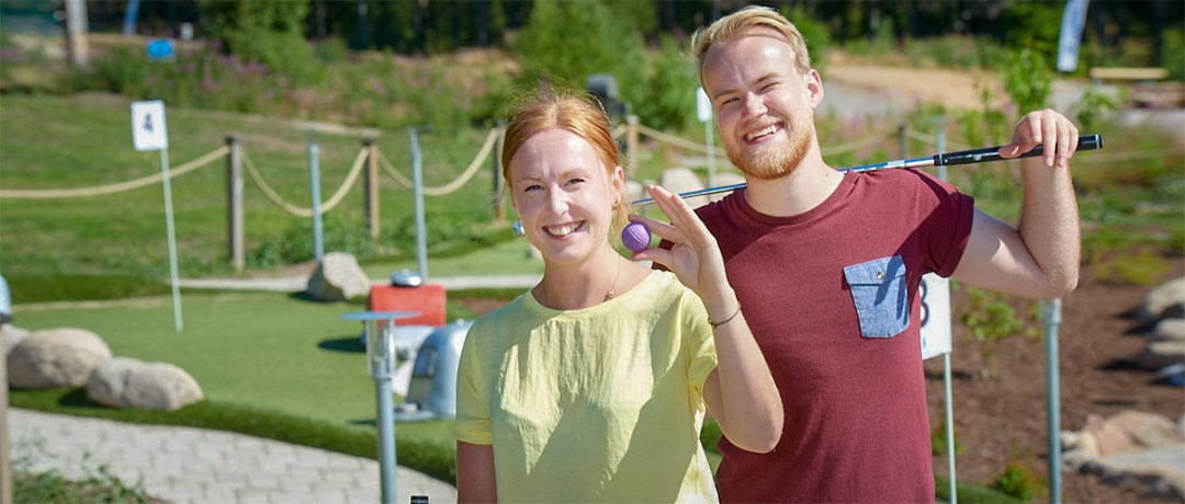 Två ungdomar spelar äventyrsgolf på Isaberg, med en av banorna bakgrunden. En perfekt aktivitet för både nybörjare och erfarna spelare i Småland.