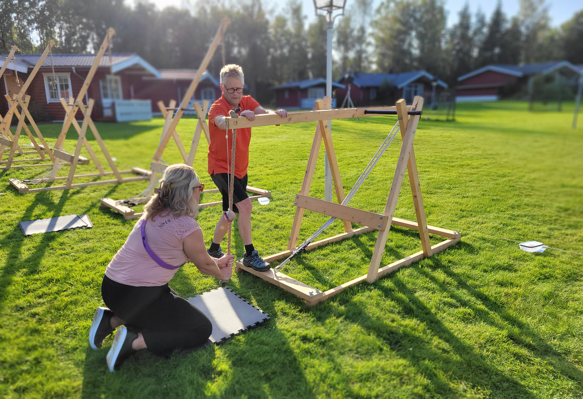 Två deltagare i den team stärkande konferensaktiviteten katapultbygge på Hestravikens gräsmatta i Småland