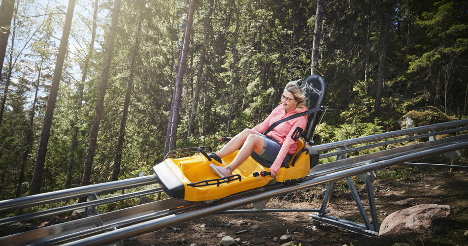 Kvinna åker rodel nedför Isabergs bana en sommardag i Hestra, Småland.